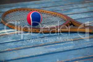Close up of red and blue ball on wooden tennis racket