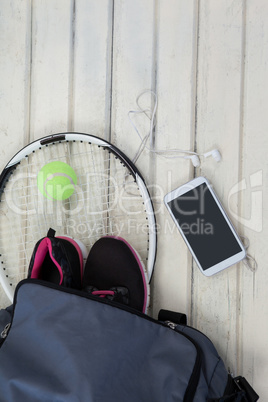 Overhead view of gray bag on sports shoes with tennis gear by mobile phone