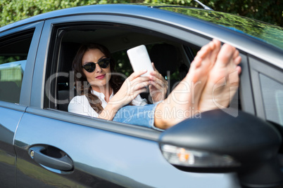 Woman taking selfie with mobile phone in car