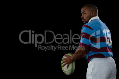 Side view of sportsman holding rugby ball while looking away
