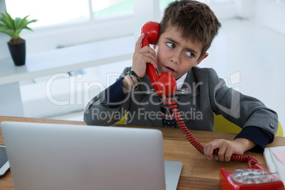 Boy as business executive talking on phone