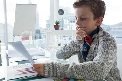 Boy as business executive verifying document