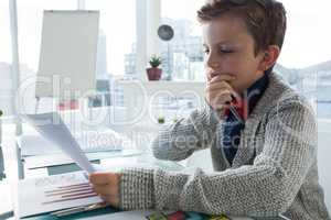 Boy as business executive verifying document