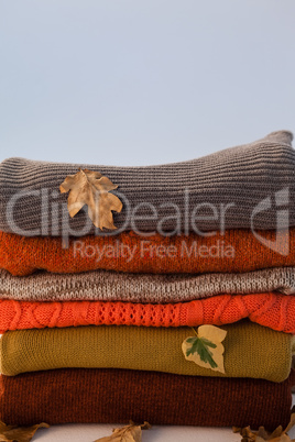 Stack of woolen clothing with autumn leaves