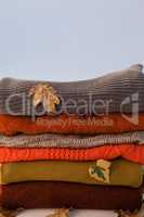 Stack of woolen clothing with autumn leaves