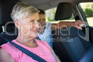 Grandmother driving a car while grandson sitting in the back seat
