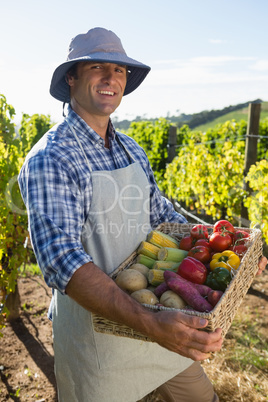 Portrait of happy man holding a basket of fresh vegetables