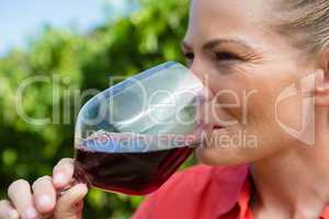 Close-up of female vintner tasting glass of wine