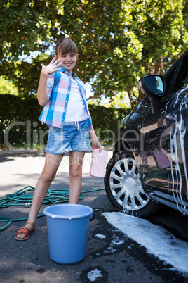 Teenage girl washing a car on a sunny day