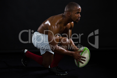 Side view shirtless man holding rugby ball