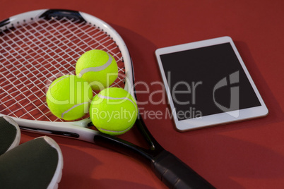 High angle view of sports shoes and digital tablet by balls on tennis racket