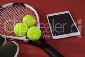 High angle view of sports shoes and digital tablet by balls on tennis racket
