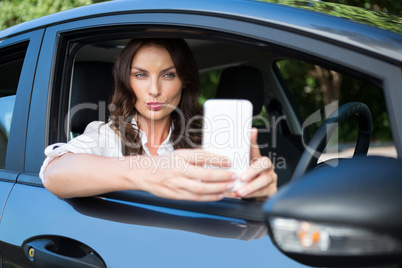 Woman taking selfie with mobile phone in car
