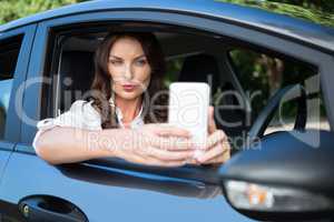 Woman taking selfie with mobile phone in car