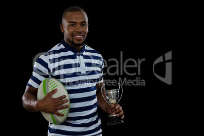 Portrait male athlete with rugby ball and trophy