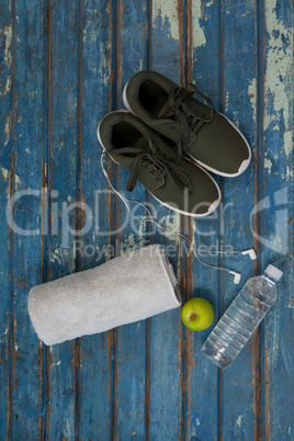 Directly above view of sports shoes and napkin by headphones with water bottle on table