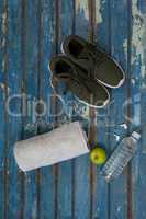 Directly above view of sports shoes and napkin by headphones with water bottle on table