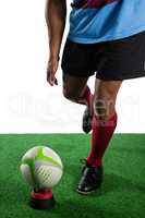 Low section of male athlete kicking rugby ball