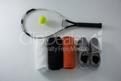 Overhead view of ball on racket by napkins and sports shoe