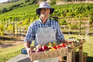 Portrait of happy farmer holding a basket of fresh vegetables