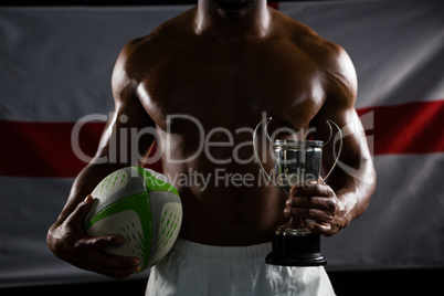 Mid section of shirtless man with trophy and rugby ball against British flag