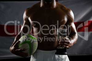 Mid section of shirtless man with trophy and rugby ball against British flag