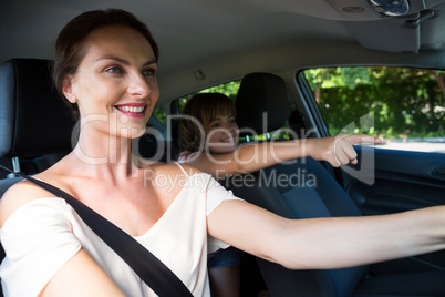 Woman driving a car while daughter sitting in the backseat of car