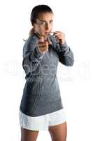 Portrait of female coach gesturing while blowing whistle