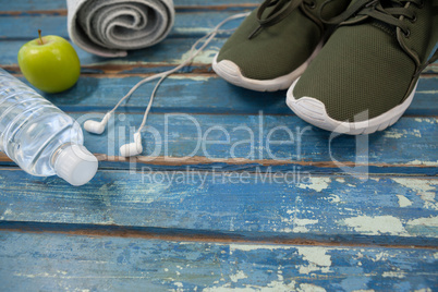 High angle view of sports shoes and napkin by headphones with water bottle