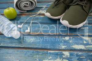 High angle view of sports shoes and napkin by headphones with water bottle
