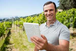 Portrait of vintner using digital tablet in vineyard