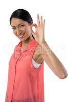 Smiling woman gesturing okay hand sign against white background