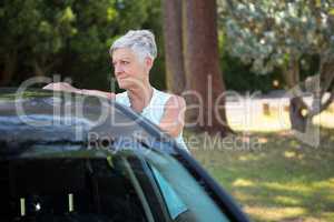 Senior woman standing beside a car