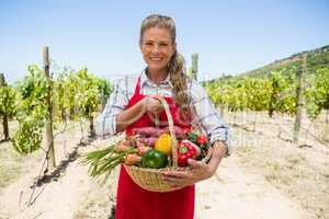 Portrait of happy woman holding a basket of fresh vegetables