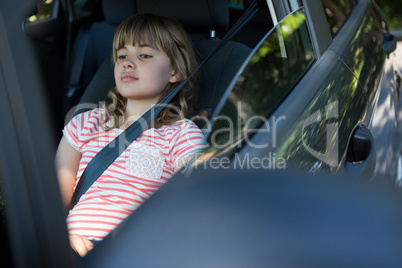 Teenage girl sitting in the back seat of car