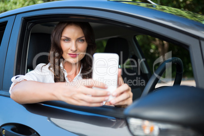 Woman taking selfie with mobile phone in car