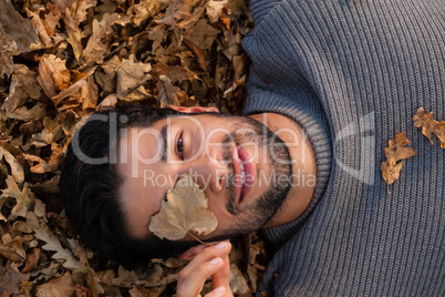 Overhead of man lying on autumn leaves