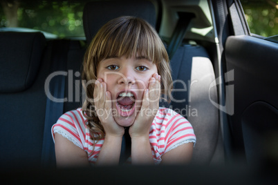 Happy teenage girl sitting in the back seat of car