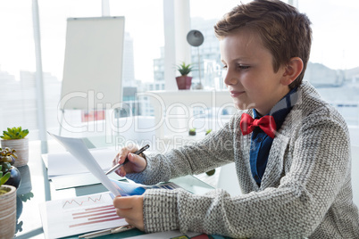 Boy as business executive verifying document