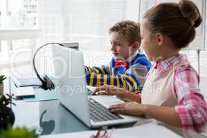 Kids as business executive interacting while using laptop