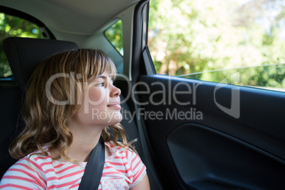 Teenage girl sitting in the back seat of car