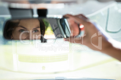 Woman looking into rear view mirror while driving a car