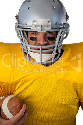 Portrait of determined American football player wearing helmet holding ball
