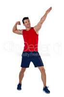 Full length of sports player flexing muscles with hand raised