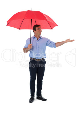 Male executive holding umbrella against white background