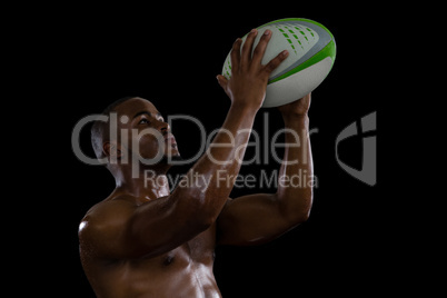 Shirtless male athlete catching rugby ball