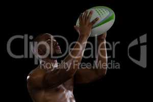 Shirtless male athlete catching rugby ball