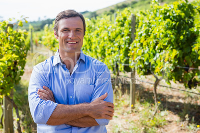 Portrait of smiling vintner standing with arms crossed