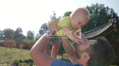 Affectionate young father lifting cute baby boy up