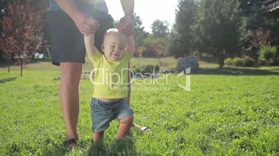 Baby boy learning to walk with father's help